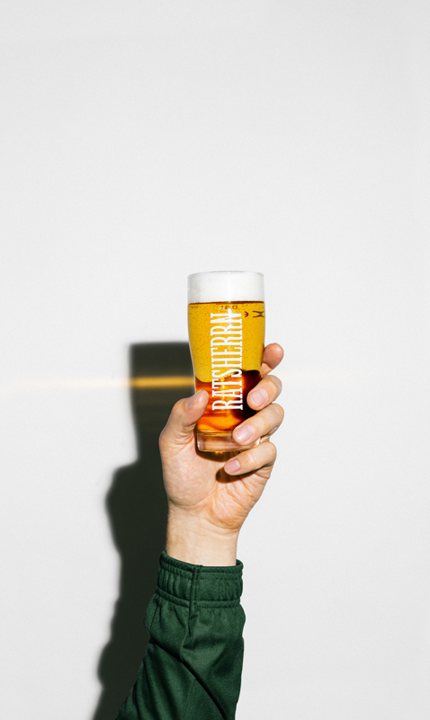 Hand hält ein gefülltes Bierglas