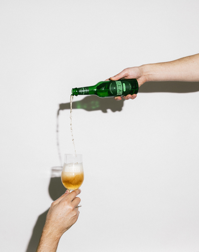Hand kippt Bier aus Ratsherrn Flasche in ein Pils Glas